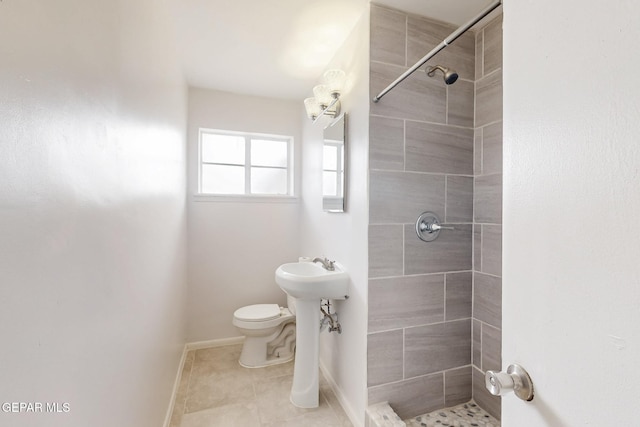 full bathroom featuring baseboards, toilet, tile patterned flooring, a tile shower, and a sink