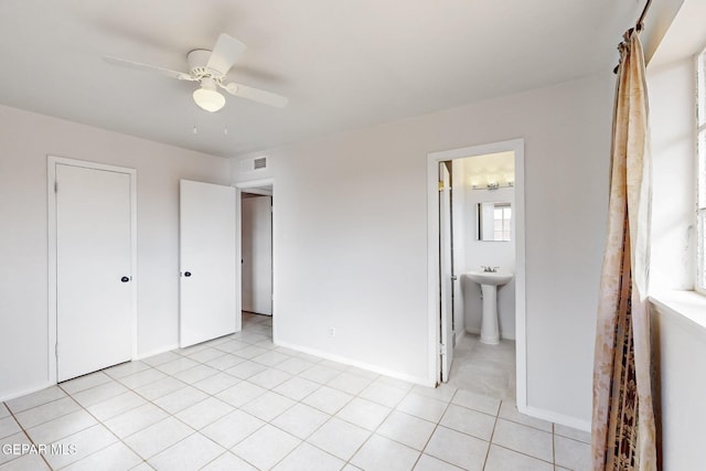 unfurnished bedroom with light tile patterned floors, visible vents, baseboards, a ceiling fan, and a sink