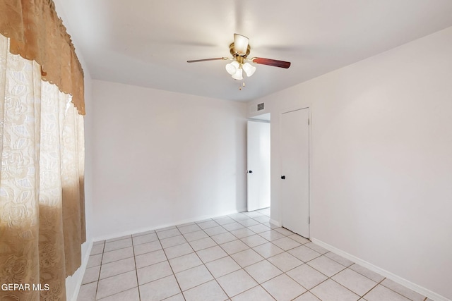 empty room with light tile patterned floors, baseboards, visible vents, and a ceiling fan