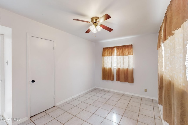 unfurnished room featuring ceiling fan, baseboards, and light tile patterned floors