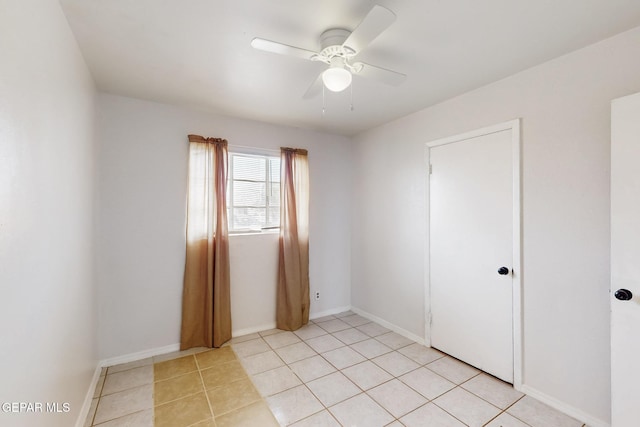 spare room with a ceiling fan, baseboards, and light tile patterned floors