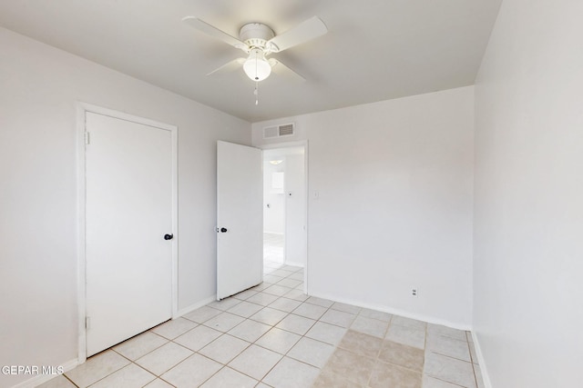 empty room featuring ceiling fan, light tile patterned floors, visible vents, and baseboards