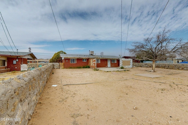 view of front of home with brick siding, fence, and driveway