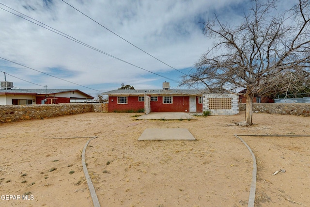 view of front of home featuring fence, a patio, and brick siding