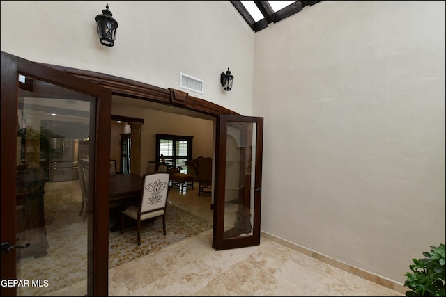 interior space featuring french doors, visible vents, a towering ceiling, and baseboards