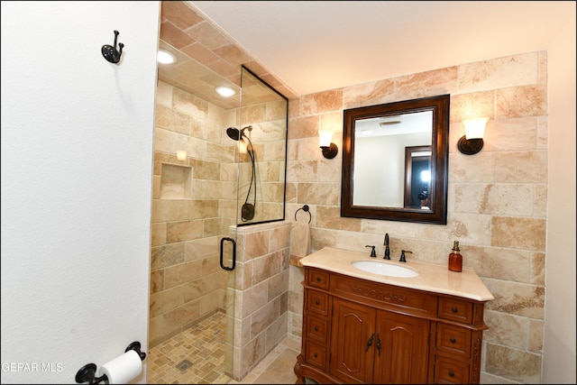 full bath with a stall shower, vanity, and tile walls