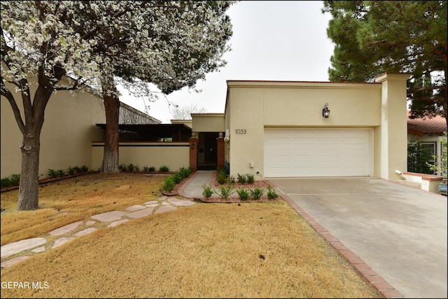 view of front of property with concrete driveway, an attached garage, and stucco siding