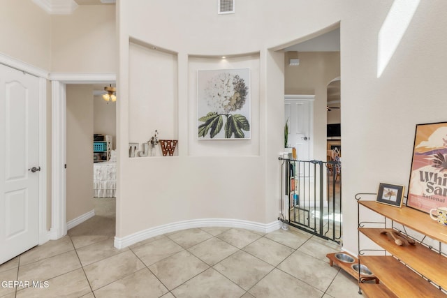 hallway featuring light tile patterned floors, arched walkways, visible vents, and baseboards