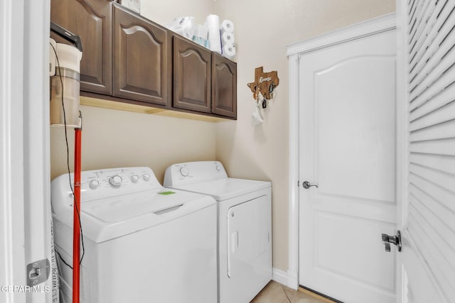 laundry area featuring light tile patterned floors, washer and clothes dryer, and cabinet space