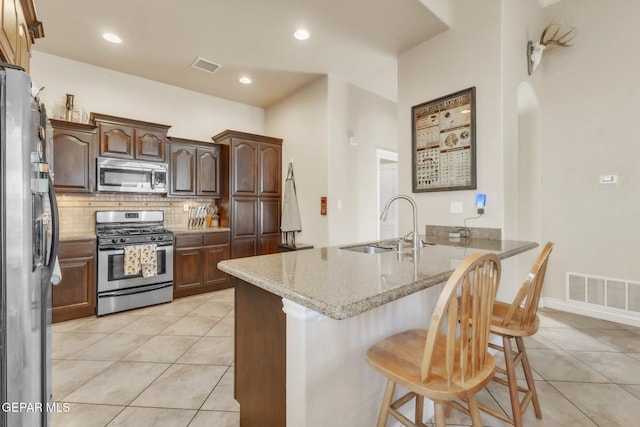 kitchen featuring a peninsula, appliances with stainless steel finishes, a sink, and visible vents