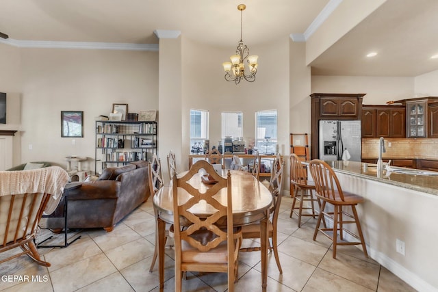 dining area featuring baseboards, ornamental molding, a chandelier, and light tile patterned flooring