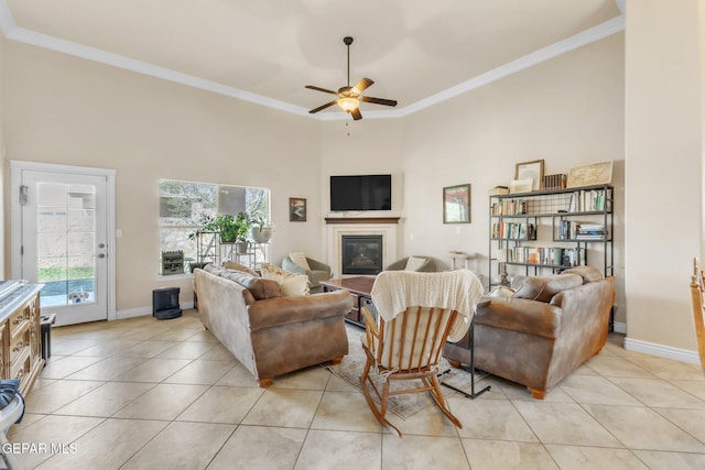 living area featuring light tile patterned floors, a glass covered fireplace, and crown molding