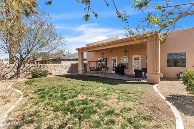 rear view of property with a patio area, a yard, and stucco siding