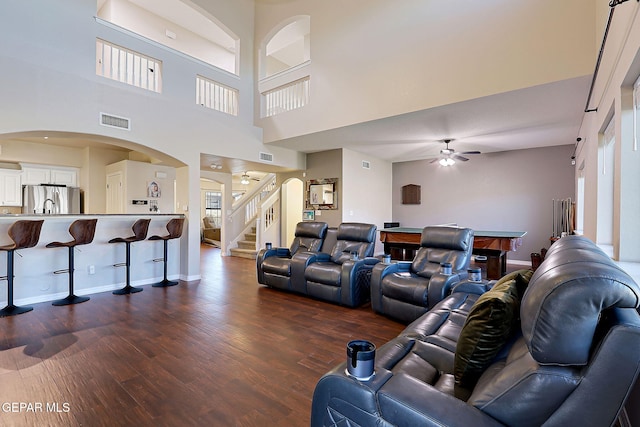 living area featuring dark wood-type flooring, visible vents, baseboards, a ceiling fan, and stairway