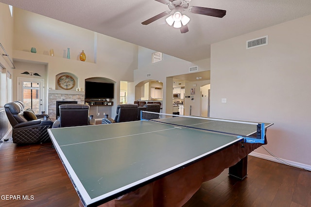 game room featuring a stone fireplace, dark wood-style flooring, and visible vents