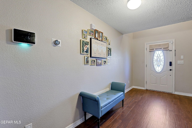 entrance foyer with a textured ceiling, a textured wall, dark wood finished floors, and baseboards