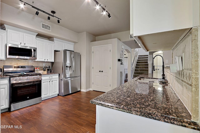 kitchen featuring dark wood-style flooring, visible vents, appliances with stainless steel finishes, white cabinets, and a sink