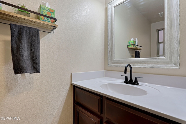 bathroom featuring visible vents, a textured wall, and vanity