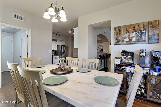 dining space featuring dark wood-style floors, visible vents, a notable chandelier, and stairs