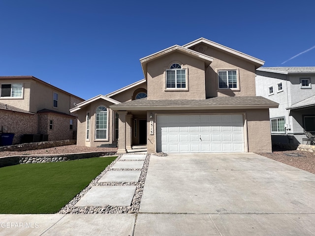 traditional-style house featuring a garage, concrete driveway, a front lawn, and stucco siding