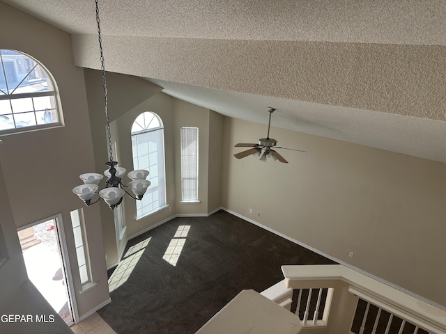 carpeted foyer entrance featuring lofted ceiling, a textured ceiling, ceiling fan with notable chandelier, and tile patterned floors