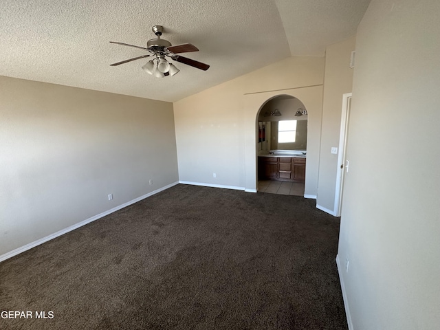 unfurnished room featuring arched walkways, carpet, lofted ceiling, ceiling fan, and a textured ceiling