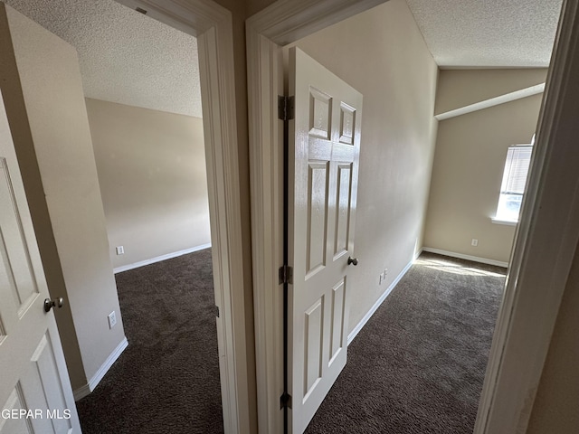 corridor with lofted ceiling, carpet floors, a textured ceiling, and baseboards