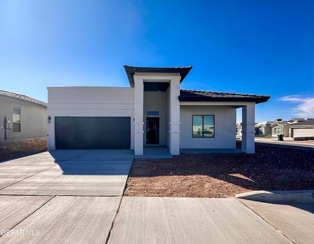 prairie-style house featuring a garage, concrete driveway, and stucco siding