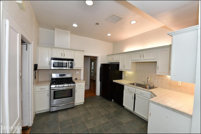 kitchen with a sink, visible vents, white cabinetry, black appliances, and tasteful backsplash