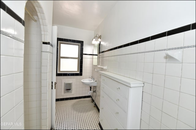 bathroom featuring a wainscoted wall, a sink, tile walls, and heating unit