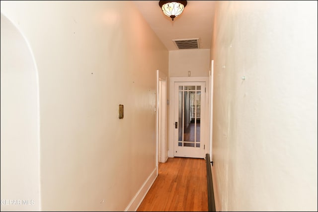 hallway featuring light wood-type flooring, baseboards, and visible vents