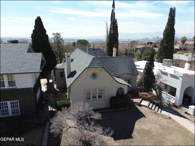 view of front of house with roof with shingles, a chimney, fence, and stucco siding