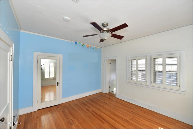 empty room featuring crown molding, ceiling fan, baseboards, and wood finished floors