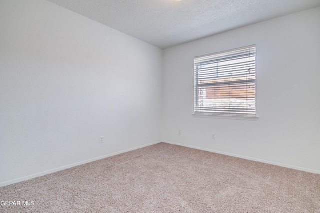 carpeted empty room featuring baseboards and a textured ceiling