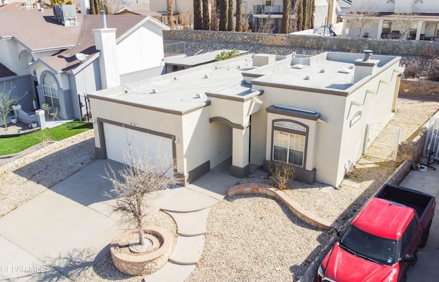 view of front of home with stucco siding, a residential view, a chimney, and driveway