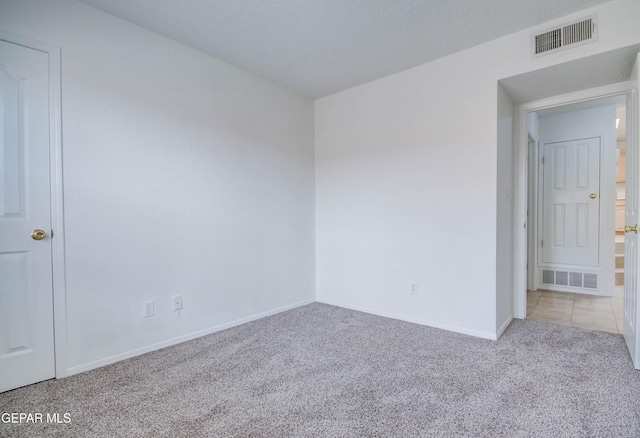 carpeted empty room featuring visible vents, baseboards, and a textured ceiling