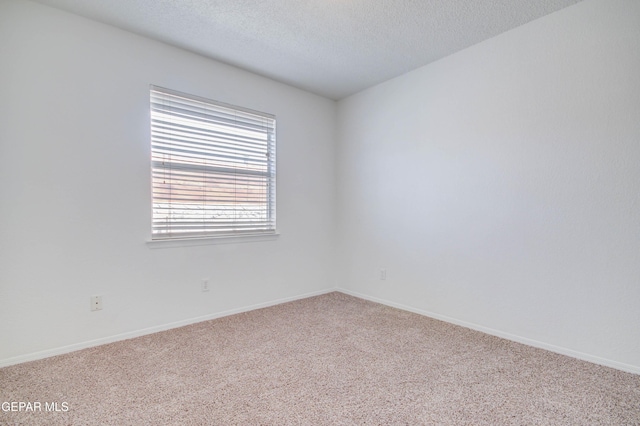 spare room featuring baseboards, carpet floors, and a textured ceiling