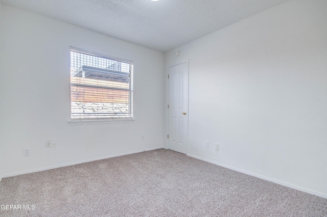 empty room featuring carpet, baseboards, and a textured ceiling