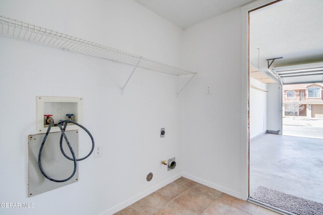 laundry room featuring baseboards, laundry area, hookup for a washing machine, a garage, and electric dryer hookup