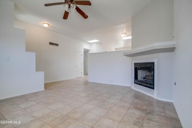 unfurnished living room with light tile patterned floors, baseboards, visible vents, a fireplace, and ceiling fan