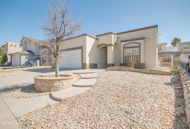 view of front of house with stucco siding, driveway, an attached garage, and a gate