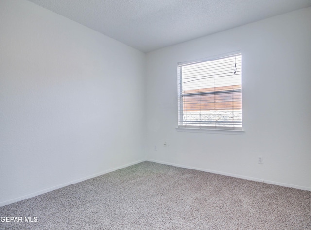 carpeted empty room with a textured ceiling and baseboards