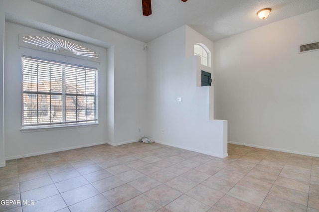 empty room featuring light tile patterned flooring, visible vents, baseboards, and ceiling fan