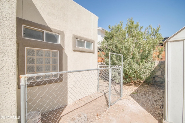 view of side of home with a gate, stucco siding, and fence