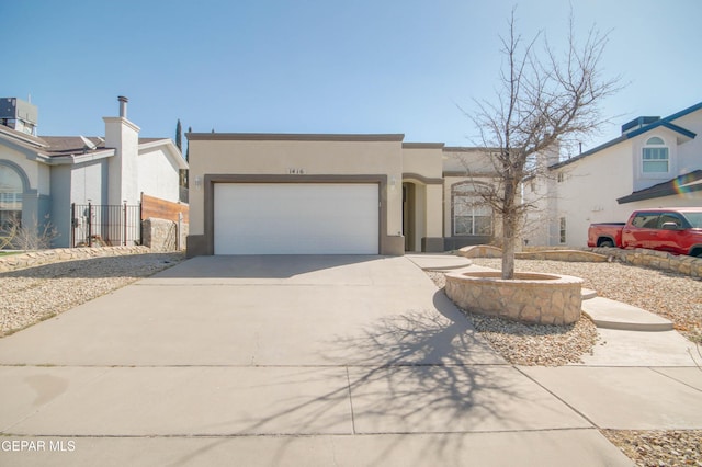 pueblo-style house with concrete driveway, a garage, and stucco siding