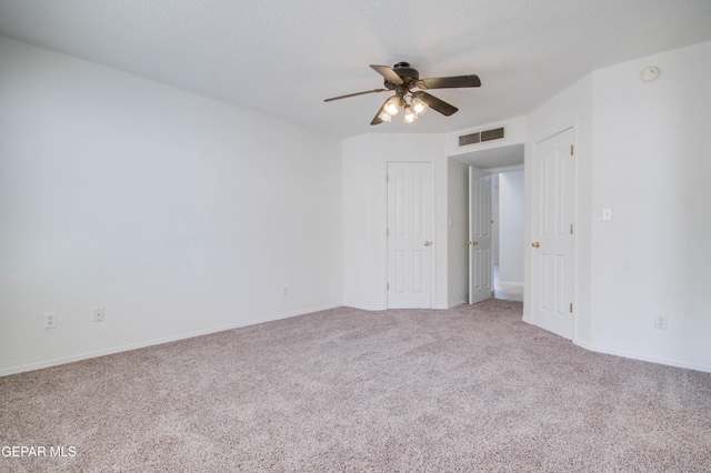 empty room with visible vents, carpet, a ceiling fan, and a textured ceiling