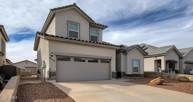 mediterranean / spanish-style house with driveway, stone siding, a garage, and stucco siding