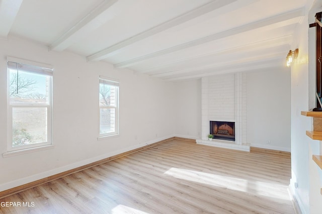 unfurnished living room with light wood-style floors, beamed ceiling, a fireplace, and baseboards