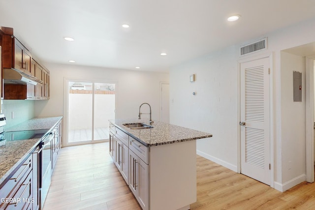 kitchen featuring visible vents, light wood finished floors, range with electric cooktop, a sink, and under cabinet range hood