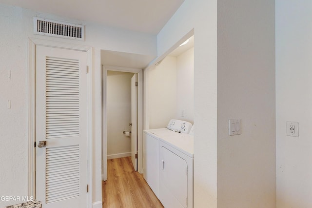 clothes washing area featuring laundry area, washing machine and dryer, visible vents, and light wood-type flooring